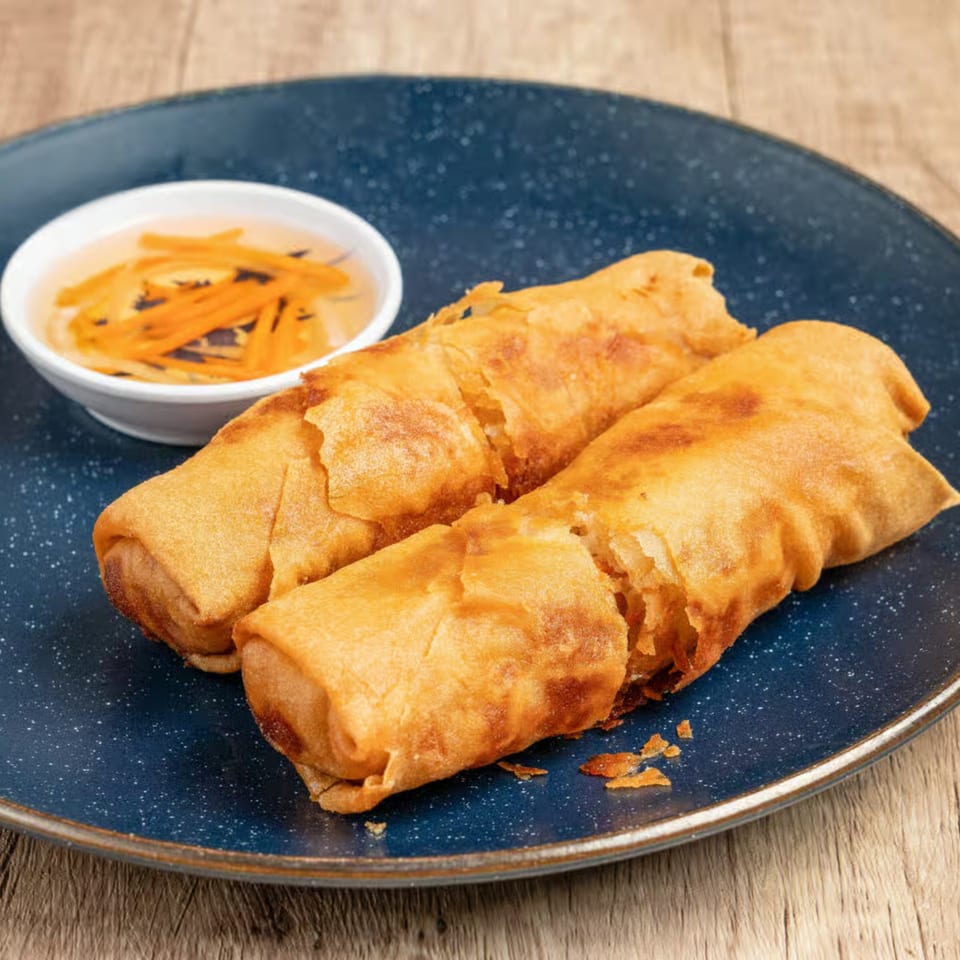 Two crispy Vietnamese fried spring rolls with a side of dipping sauce on a blue plate.