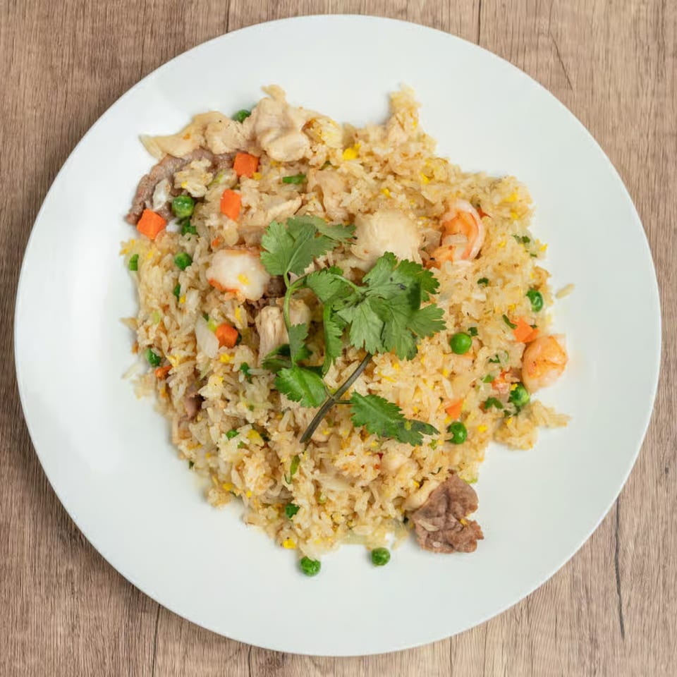 Green Basil's Vietnamese fried rice with shrimp, chicken, beef, peas, carrots, and cilantro on a white plate.